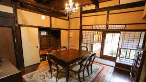 a dining room with a wooden table and chairs at Machiya Club Honkan in Omihachiman