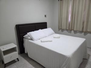 a bedroom with a white bed with a black headboard at Condominio Delville 2 quartos in Porto Velho