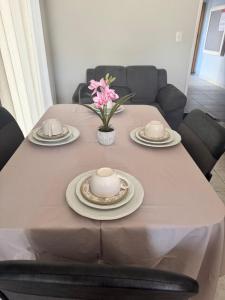 a table with plates and a vase with flowers on it at Condominio Delville 2 quartos in Porto Velho