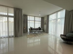 a living room with a couch and some windows at Spacious Fully Furnished 6BR Villa in Damac Hill2 in ‘Ūd al Bayḑāʼ