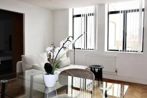 a living room with a glass table with a vase of flowers at Chelmsford Town Centre, Modern 1 Bed Apartment in Chelmsford