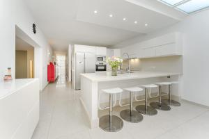 eine Küche mit weißen Schränken und einer Theke mit Stühlen in der Unterkunft Palmera Sky Terrace Suite in Las Galletas