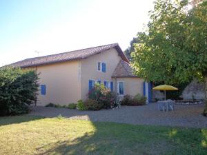 a house with a table and an umbrella in the yard at A lines in Montsoué