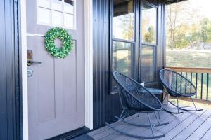 two chairs on a porch with a door and a wreath at Bourbon Barrel Cottages #5 on Ky Bourbon Trail in Lawrenceburg