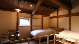 two beds in a room with wooden ceilings at まちや倶楽部別館 in Omihachiman
