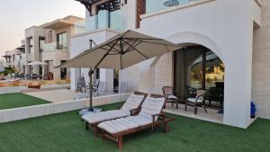 a patio with two chairs and an umbrella at Hawana Salalah Poolside Apartment in Salalah