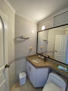 a bathroom with a toilet and a large mirror at LAGOS DEL PEÑON 180 metros in Girardot