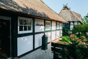 伦布鲁Cottage mit Kamin und Garten, seenah的一间茅草屋顶、有窗户、有鲜花的农舍