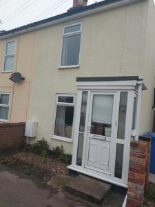 ein Haus mit einer weißen Tür und Fenstern in der Unterkunft Coastline cottage in Pakefield
