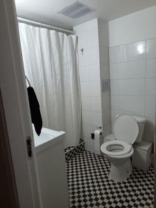 een badkamer met een toilet en een zwart-witte tegelvloer bij GuestHouse in Santiago