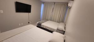 a small room with two beds and a flat screen tv at Apto 2 Quartos com Suíte, Garagem, 300m da Praia in Fortaleza