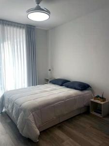 a white bedroom with a large bed with blue pillows at Dzain 1 - PISCINA -Gym- Cochera - Parrilla- Playromm- cercania Garrahan, favaloro, Britanico in Buenos Aires +30 photos