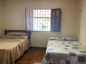 zwei Betten in einem Zimmer mit Fenster in der Unterkunft Casa Confortavel em balneario Alter do Chão Santarem Pará in Santarém