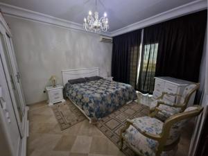 a bedroom with a bed and a chair and a chandelier at Résidence Tunis Carthage in Ariana