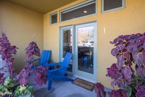 twee blauwe stoelen voor een deur met paarse bloemen bij Hideaway in the Heart of Downtown Moab in Moab
