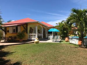 een huis met een tuin met stoelen en een zwembad bij La Jolie in Baie-Mahault
