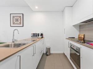 een keuken met witte kasten en een spoelbak bij Tranquil 1-Bed Apartment with Courtyard, Pool, BBQ in Phillip