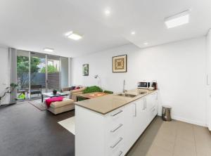een keuken met witte kasten en een woonkamer bij Tranquil 1-Bed Apartment with Courtyard, Pool, BBQ in Phillip +4 foto's