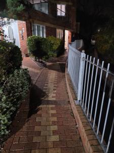 a brick sidewalk with a white fence in front of a building at 4 School Path in Ironbridge