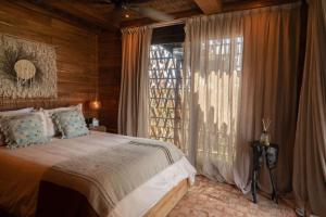 a bedroom with a bed and a large window at Nômade Temple Holbox in Holbox Island