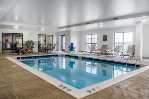 a swimming pool in a building with chairs and tables at Comfort Suites Manheim - Lancaster in Manheim