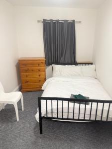 a bedroom with a bed and a dresser and a chair at Saunders house in Gillingham