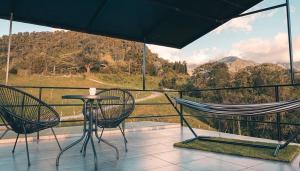a balcony with a hammock and a table and chairs at Glamping La Maestranza con desayuno incluido in Villamaría