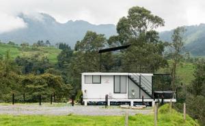 a small white house in a field with trees at Glamping La Maestranza con desayuno incluido in Villamaría