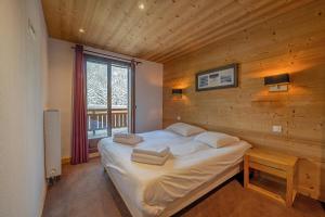 a bedroom with a large bed in a wooden wall at l'Ours Bleu A35 - Ski in Ski out - Happy Rentals in Vallorcine