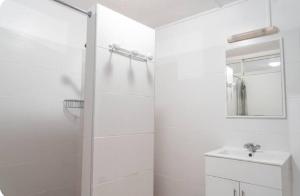a white bathroom with a shower and a sink at Studio Teava in Papeete