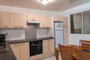 a kitchen with a white refrigerator and a table at Studio Teava in Papeete