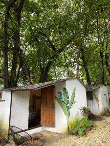 a small white shed with a wooden door and trees at Maudie in Santa Teresa Beach