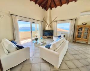 a living room with two white couches and a television at Luxury apartment Ginestra sea view with common swimming pool just 50 mt from the beach in Golfo Aranci