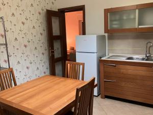 a kitchen with a wooden table and a white refrigerator at Casa Cuore Mother Ross in Ariano Irpino