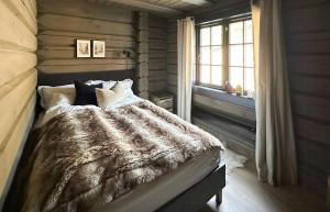 a bedroom with a bed with a comforter and a window at Cozy Log Cabin With A View Over Hedmarken in Løten