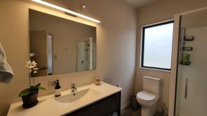 a bathroom with a sink and a toilet and a mirror at Pheasant Hill Hideaway 10 min to Waihi Beach in Athenree +28 photos