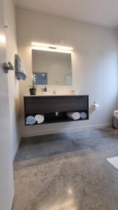 a bathroom with a sink and a large mirror at Pheasant Hill Hideaway 10 min to Waihi Beach in Athenree