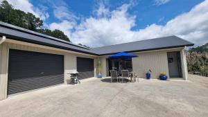 a garage with a table and a blue umbrella at Pheasant Hill Hideaway 10 min to Waihi Beach in Athenree