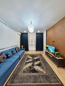 a living room with a blue couch and a large screen at Rich Life in Almaty