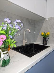 a kitchen counter with a sink and flowers in a vase at Rich Life in Almaty