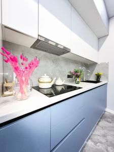 a kitchen with white cabinets and pink flowers in a vase at Rich Life in Almaty +40 photos