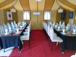 a room with long tables and white chairs at Afraklie Camp in Merzouga