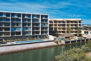 ein Apartmenthaus neben einem Wasserkörper in der Unterkunft Modern Condo with Pool in Marina Mazatlan in San Rafael