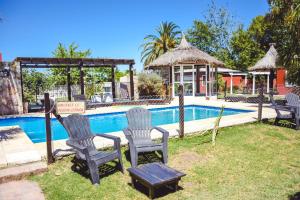 two chairs and a table next to a swimming pool at las moraditas in Chascomús