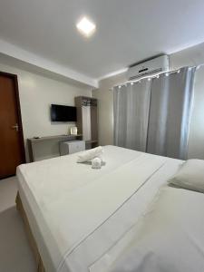 a bedroom with two large white beds and a tv at Vila Mar Eco Hotel in Parnaíba