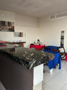 a kitchen with a granite counter top and a table at Hotel Acácia in Tangara da Serra +18 photos