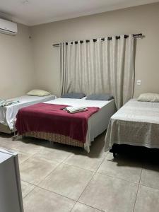 Hotel Acácia في تانجارا دا سيرا: غرفة نوم بها سريرين وستارة