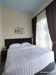 a bedroom with a large white bed and a window at AJA Tumapaksewu Homestay in Pronojiwo