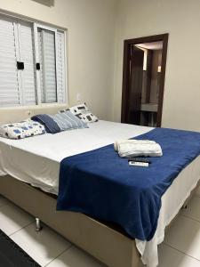 a bedroom with a large bed with a blue blanket at Hotel Acácia in Tangara da Serra