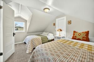 a attic bedroom with two beds and a window at Meadowsweet Farm- Sleeps 18, Outdoor Kitchen in Talent